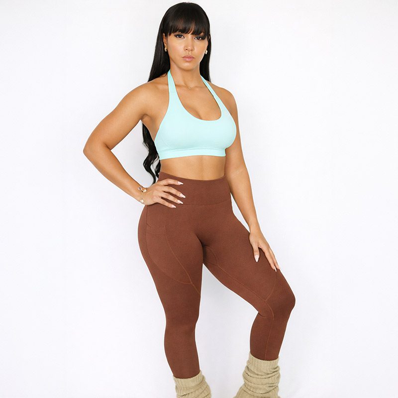 Woman wearing mocha brown high-waisted sculpt leggings with side pocket and mint sports bra